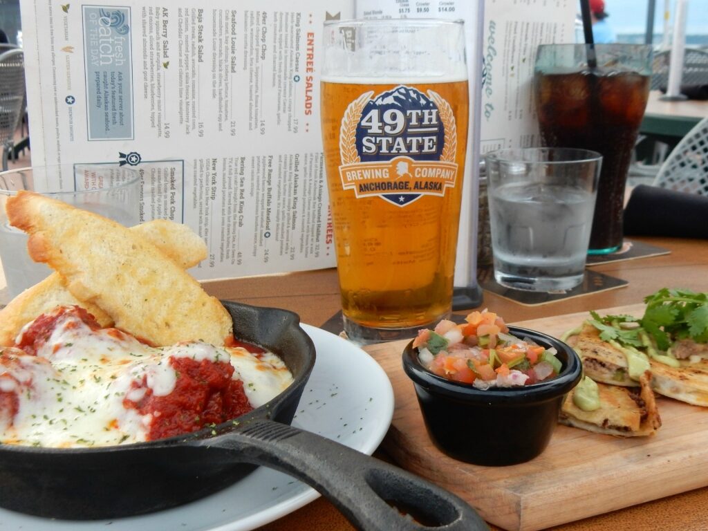 A glass of beer from 49th State Brewing with food
